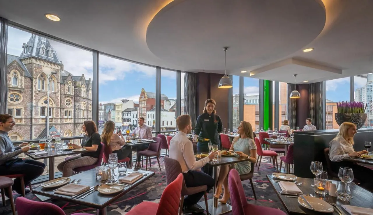 a group of people sitting at tables in a restaurant at Clayton Hotel Cardiff in Cardiff