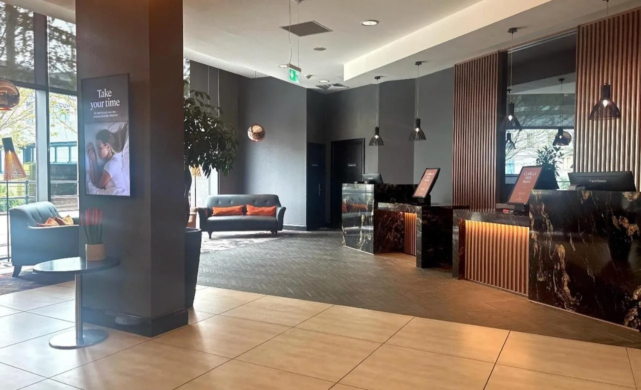 a lobby with a waiting area with chairs and a desk at Clayton Hotel Cardiff in Cardiff