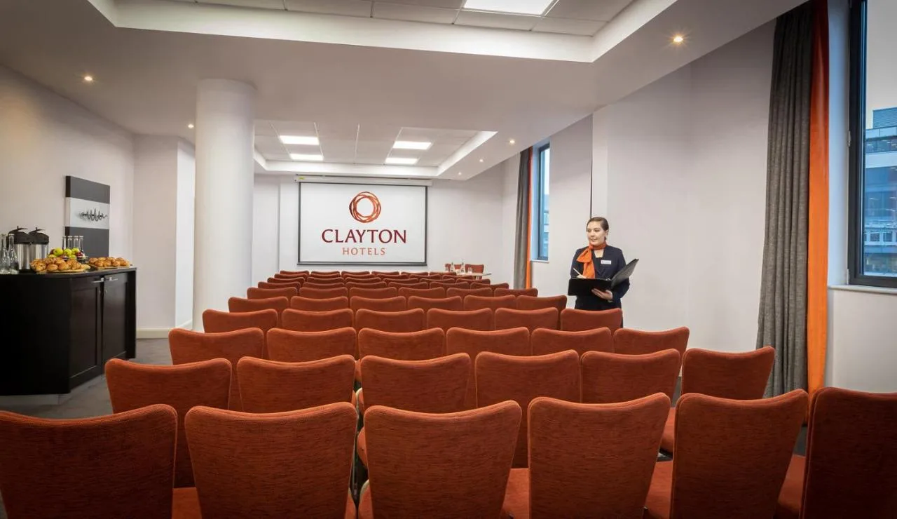a woman standing in a conference room with orange chairs at Clayton Hotel Cardiff in Cardiff