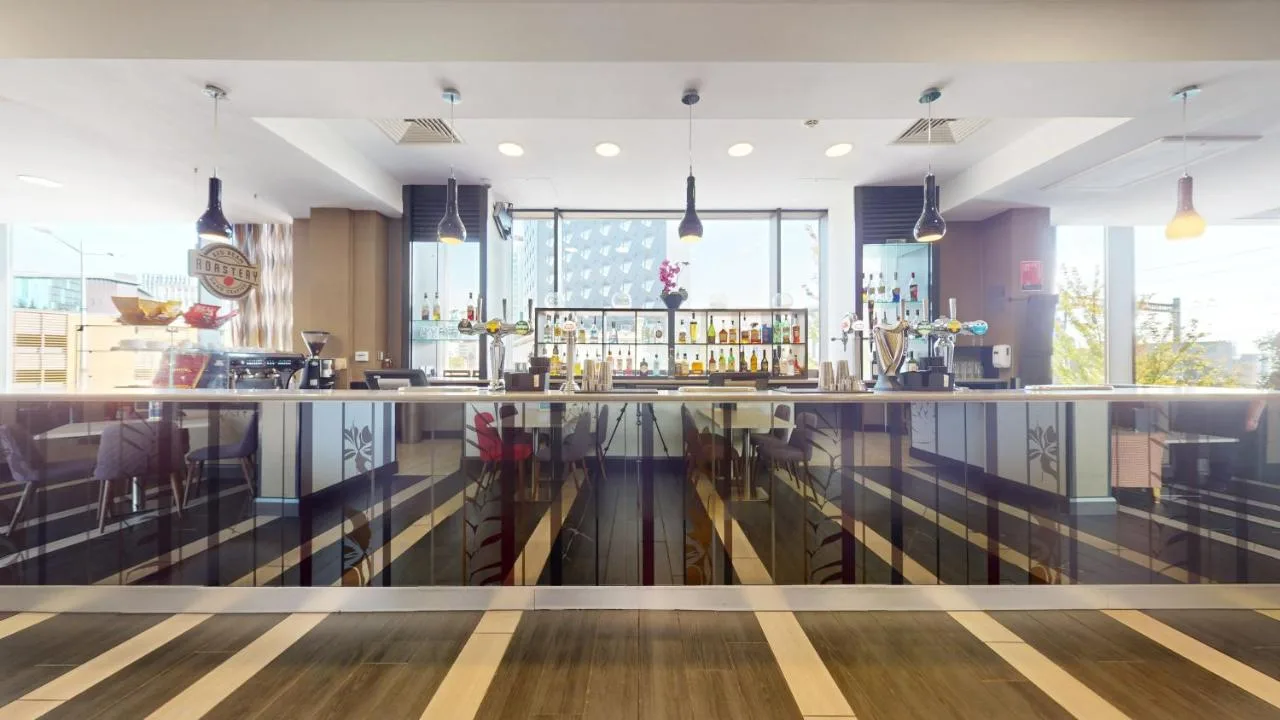a restaurant with a bar with tables and chairs at Clayton Hotel Cardiff in Cardiff